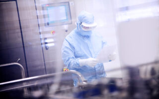 Gowned scientist in a lab holding a sterile single use product bag