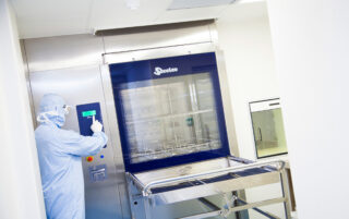 Fully gowned, small molecule manufacturing scientist loading a glass washer