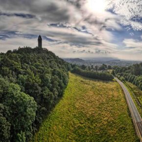 Panoramic view of The National Wallace Monument, sun in the blue sky overlooking the Symbiosis buildings at Stirling Innovation Park.