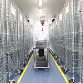 Symbiosis technician wheeling trolley through drug product storage racks